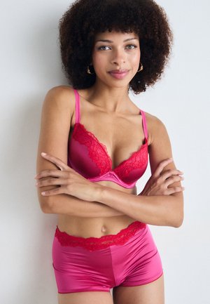Soutien-gorge en dentelle rose avec un short assorti, featuring un bord en dentelle transparente et une texture lisse semblable à du satin. Conçu avec des bretelles réglables.