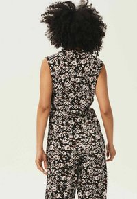 Svart ärmlös jumpsuit med blommiga och abstrakta mönster i vitt och rosa toner, med en figursydd midja och vida ben.