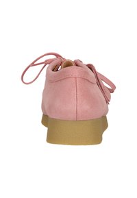 Scarpa stringata in suede rosa con una spessa suola in gomma beige, mostrata da dietro su uno sfondo bianco.