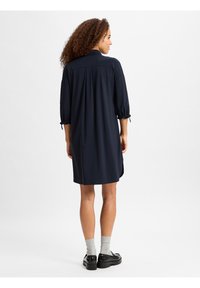 Marineblaues kurzes Kleid mit lockerem Schnitt, gerafften Ärmeln und seitlichen Schlitzen. Das weiche Material und der geknöpfte Kragen unterstreichen das lässige Design.