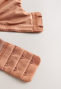 Spallina e chiusura del reggiseno color malva, caratterizzate da un tessuto morbido, una texture liscia e ganci coordinati con tre opzioni di regolazione.