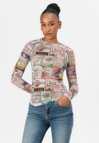 Long-sleeve graphic top featuring a colorful collage of vintage gas station signs, made of stretchy fabric with a fitted design.