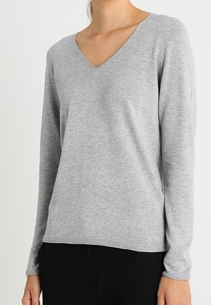 Haut gris à manches longues avec un col en V, fabriqué dans un tissu doux et texturé. Design simple, sans motifs ni embellissements visibles.