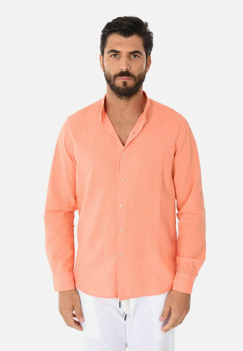 Camicia di lino color pesco con bottoni frontali, maniche lunghe e vestibilità rilassata. Presenta un colletto e un design minimalista.