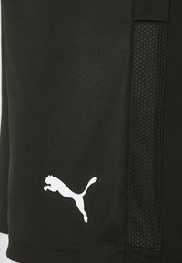 Pantalones cortos deportivos negros hechos de una tela suave con paneles laterales de malla. Presenta un logo blanco de Puma en la parte inferior izquierda.