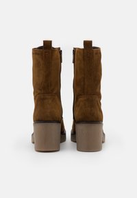 Brązowe zamszowe botki za kostkę z zaokrąglonym noskiem, solidnym obcasem typu słupek oraz teksturowaną gumową podeszwą. Dwa boczne zamki ułatwiające zakładanie.