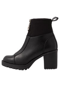 Schwarzer Knöchelstiefel mit einem klobigen Absatz, der eine glatte Lederaußenseite, elastische Einsätze und einen Reißverschluss an der Seite aufweist. Strukturiertes Sohlenprofil.