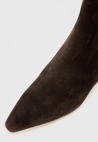 Rudos zomšu kulkščių batai su smailiu pirštu ir lygaus paviršiaus, turintys besiūlį dizainą ir jokių matomų detalių.