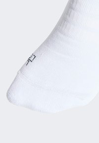 Calcetín blanco de algodón con textura acanalada y puntera reforzada. Un pequeño logo negro es visible cerca del tobillo.