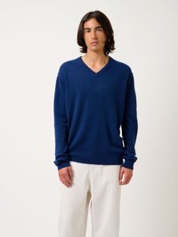 Navyblauw V-hals trui van zacht materiaal, met lange mouwen en geribbelde manchetten, gecombineerd met lichte, losse broek.