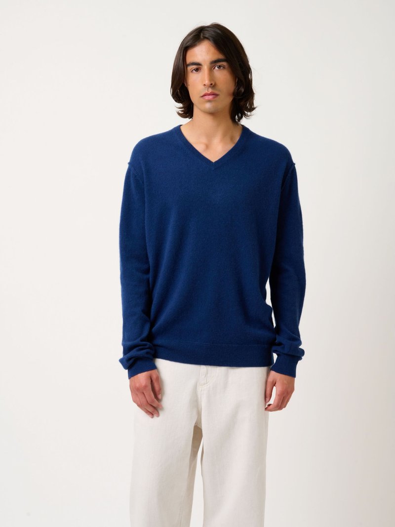 Navyblauw V-hals trui van zacht materiaal, met lange mouwen en geribbelde manchetten, gecombineerd met lichte, losse broek.