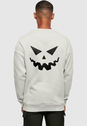 Lys grå sweatshirt med et stort sort græskar ansigt grafisk på bagsiden. Fremstillet af blødt stof med lange ærmer og rund hals.
