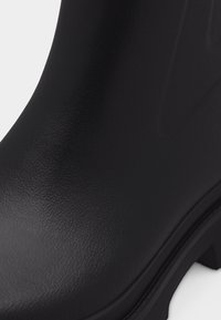 Nahaufnahme einer strukturierten schwarzen Lederstiefelspitze und eines Teils der Sohle mit geriffeltem Profil.