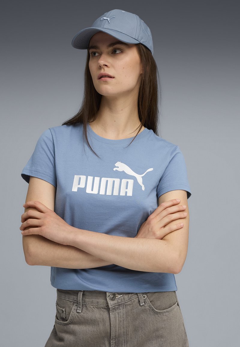 Šviesiai mėlynas medvilninis marškinėlis su baltu "PUMA" logotipu ir puma, šuoliuojančia grafika. Sutampa su šviesiai mėlynu kepurėle. Kasdienis fasonas.