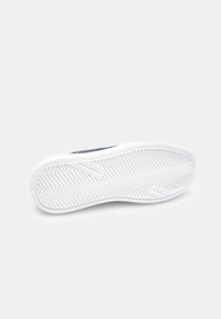 Fehér sneaker talp, halom mintával. Kék felsőrész, sima textúrával, kontrasztos fehér középtalppal és minimális dizájnnal.