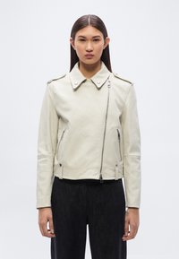 Δερμάτινο μπουφάν για μοτοσικλετιστές σε ανοιχτό μπεζ χρώμα με γιακά που κλείνει με κουμπί, διαγώνιο φερμουάρ και πλαϊνές τσέπες. Λείο υλικό και εφαρμοστή σχεδίαση.