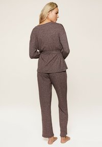 Ruskeasta heatherista valmistettu loungwear-setti, joka sisältää pitkähihaisen paidan, jossa on rento istuvuus ja vyötärölle sidottava vyö, sekä suorat lahkeet.