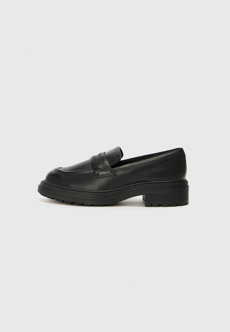 Black leather loafers with a low block heel, featuring a rounded toe and decorative stitching on the upper. Textured rubber sole.