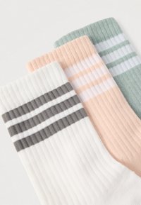 Három pár zokni szettje: egy fehér szürke csíkokkal, egy rózsaszín világos csíkokkal, és egy zöld fehér csíkokkal, mind bordázott textúrával.