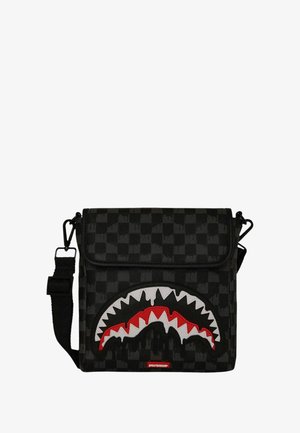 Bolso cruzado de cuadros negros con correa ajustable, cierre de solapa y un gran diseño de boca de tiburón en rojo, blanco y negro en la parte frontal.