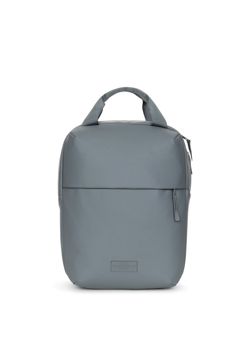 Mochila gris hecha de un material liso y duradero. Presenta un asa en la parte superior, un bolsillo con cremallera en el frente y un diseño rectangular limpio con un marcado sutil.