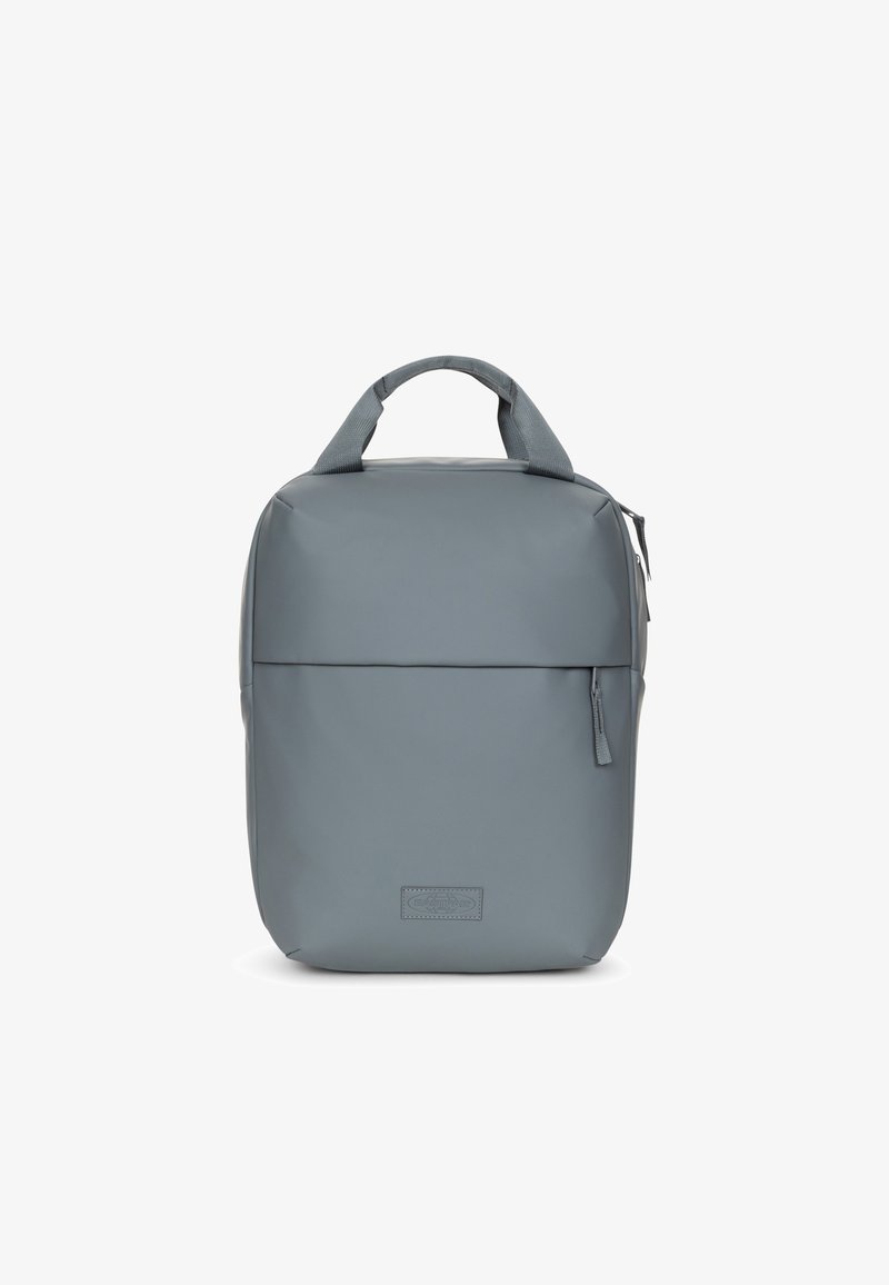 Zaino grigio realizzato in materiale liscio e resistente. Presenta un manico superiore, una tasca frontale con zip e un design pulito e rettangolare con un branding sottile.