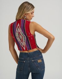 Stickad kort topp med klara röda, lila och vita geometriska mönster; matchad med mörkblå denimjeans med en läderlogo.