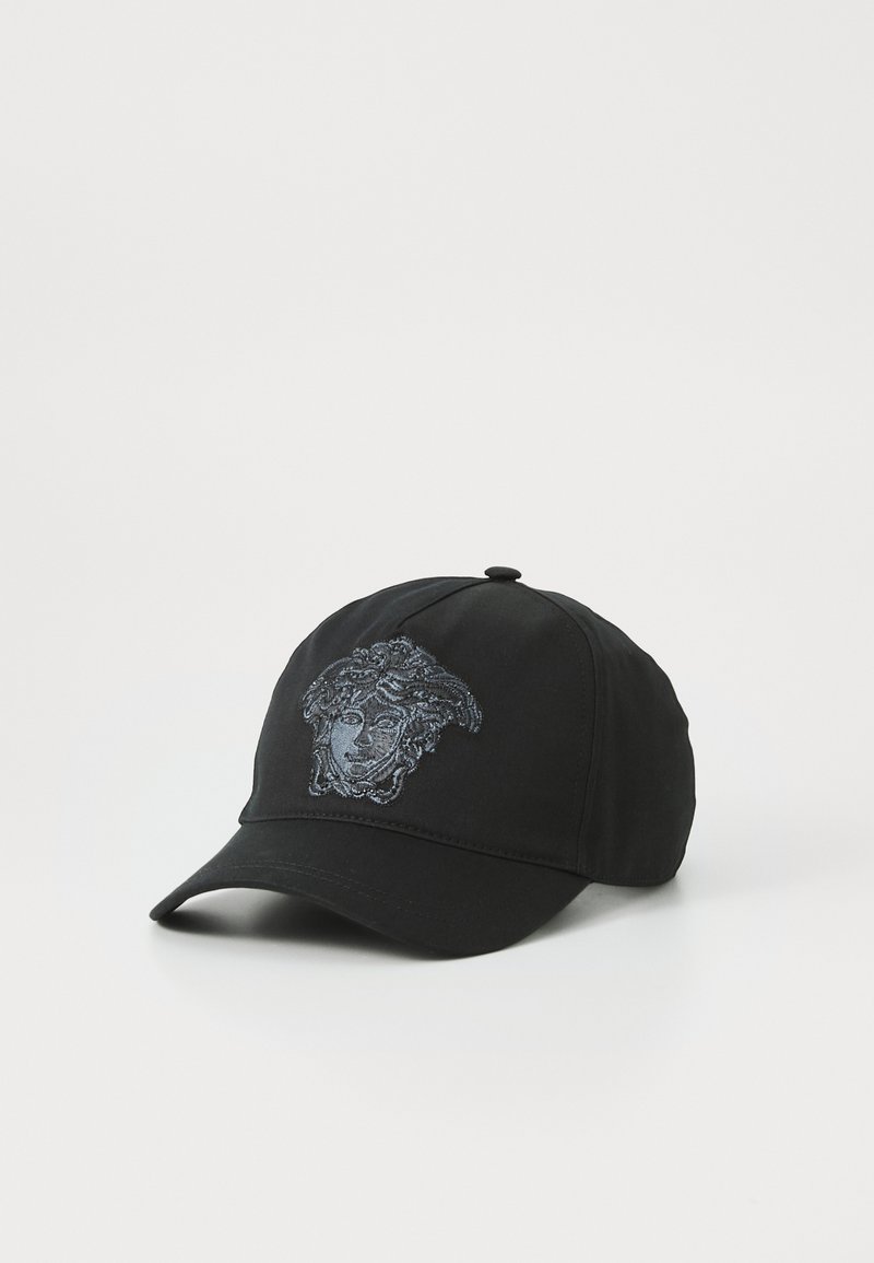 Casquette de baseball noire avec un graphisme brodé d'un visage aux cheveux détaillés. Le tissu a une texture lisse et une visière courbée.