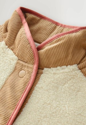 Braune Cordstoff mit einem flauschigen crema Fleece-Bereich, veredelt mit einem rosa Besatz und einem hellbraunen Knopf, der ein gemütliches, geschichtetes Design präsentiert.