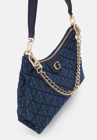 Borsa in denim trapuntato blu navy con tracolla in catena dorata, dotata di chiusura con zip e un accento del logo su un pannello testurizzato.