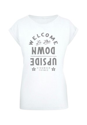 Hvid t-shirt med korte ærmer, der har et grafisk print med teksten "VELKOMMEN TIL DEN OMVENDTE VERDEN" i grå, med dekorative elementer.