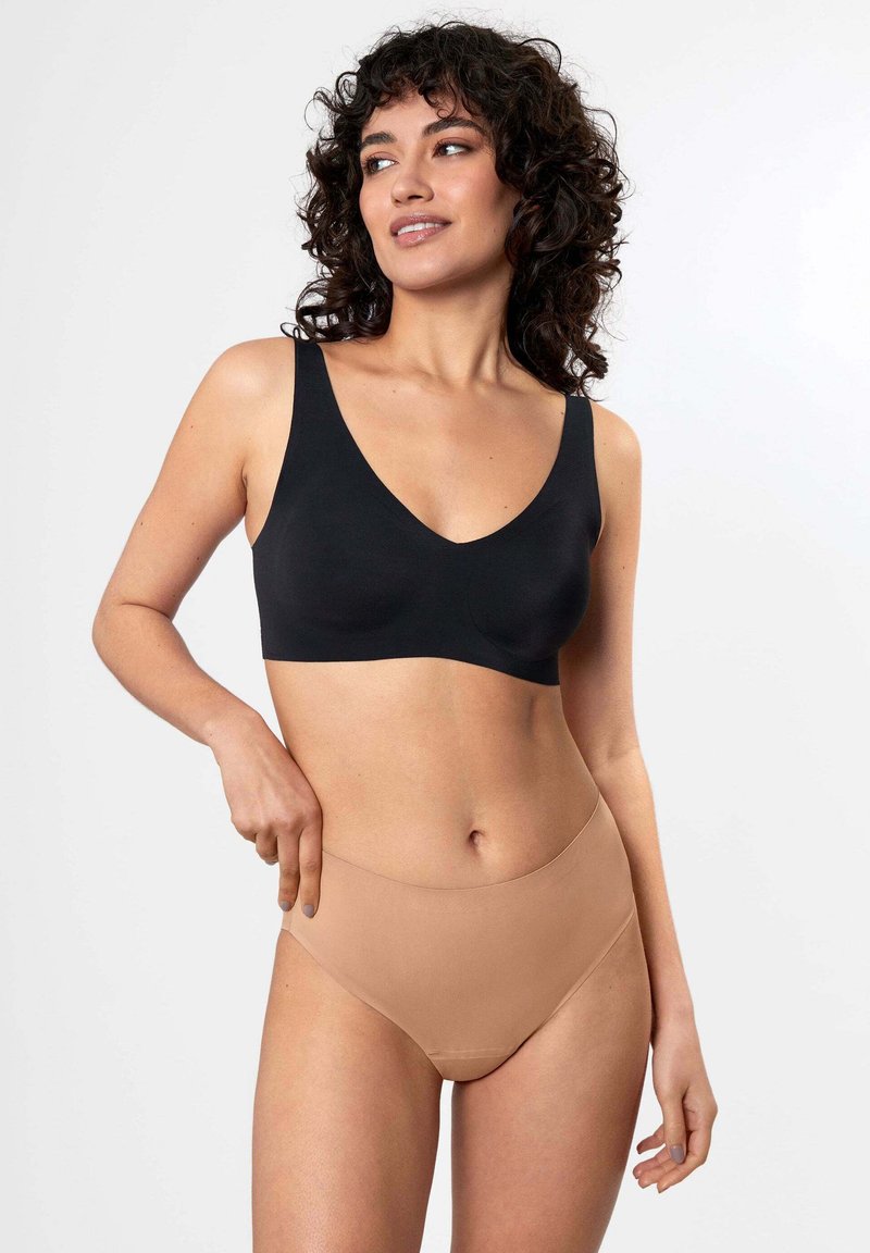 Schwarzer Bralette mit breiten Trägern und tiefem V-Ausschnitt, kombiniert mit hellbeigen nahtlosen hochgeschnittenen Unterhosen. Weicher, dehnbarer Stoff, minimale Nähte.