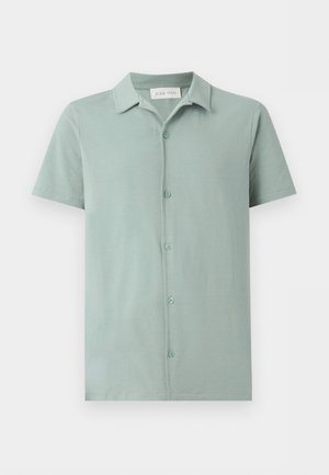 Ανοιχτοπράσινο πουκάμισο με κοντά μανίκια και γιακά, πέντε κουμπιά μπροστά και ετικέτα Pier One μέσα στον γιακά.