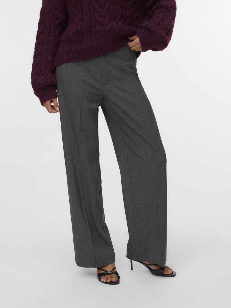 Sive široke hlače po meri z teksturirano površino, v kombinaciji z grobim vijoličnim puloverjem iz pletenine in črnimi sandali z visokimi petami in trakovi.