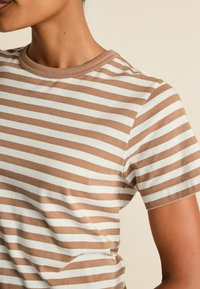Braun- und cremegestreiftes T-Shirt aus Baumwolle, mit rundem Halsausschnitt und kurzen Ärmeln, gerader Passform und weicher Textur.