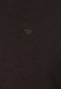 Maglione a maglia marrone scuro con un logo tonale e sottile sul petto. La texture è liscia con un fine motivo a coste in tutto il capo.