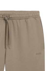 Pantalon de survêtement beige à taille élastique avec cordons de serrage et logo BOSS subtil brodé près de la poche droite.