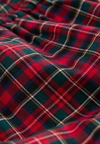 Tissu tartan rouge, vert et bleu marine avec un motif à carreaux classique comprenant des lignes fines blanches et jaunes qui se croisent.