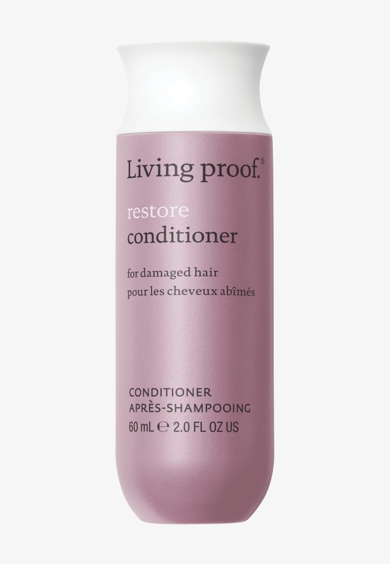 Fles Living Proof Restore Conditioner, roze met witte dop, 60 ml, gelabeld voor beschadigd haar in het Engels en Frans.