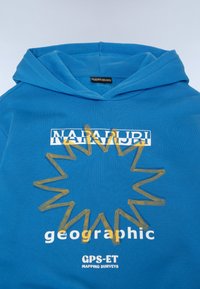 Modra kapuca s kenguru žepom; vsebuje grafiko sonca in besedilo "NAPAPIJRI" ter "geografski" v belih in rumenih odtenkih. Mehek bombažni material.
