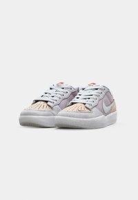 Nike teniske v sivi, bež in sivkasti barvi. Imajo nubuk in usnje ter perforirane detajle na prstih, pa tudi gumijast podplat.