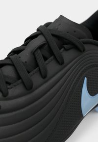 Κοντινό πλάνο μαύρου αθλητικού παπουτσιού με μαύρα κορδόνια και ανοιχτό μπλε λογότυπο Nike σε υφασμάτινο πλάγιο πάνελ.