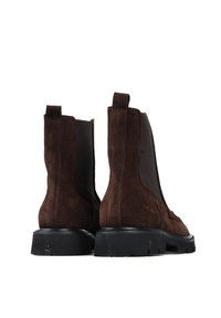 Brązowe zamszowe botki z elastycznymi panelami po bokach, uchwytami do wsuwania oraz teksturowanymi czarnymi gumowymi podeszwami. Charakteryzują się gładkim, sięgającym kostki fasonem.