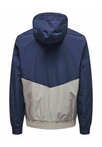 Marineblauwe en lichtgrijze windjack met capuchon, voorzien van een chevronpatroon, elastische manchetten en een_getailleerde zoom voor een slim fit.