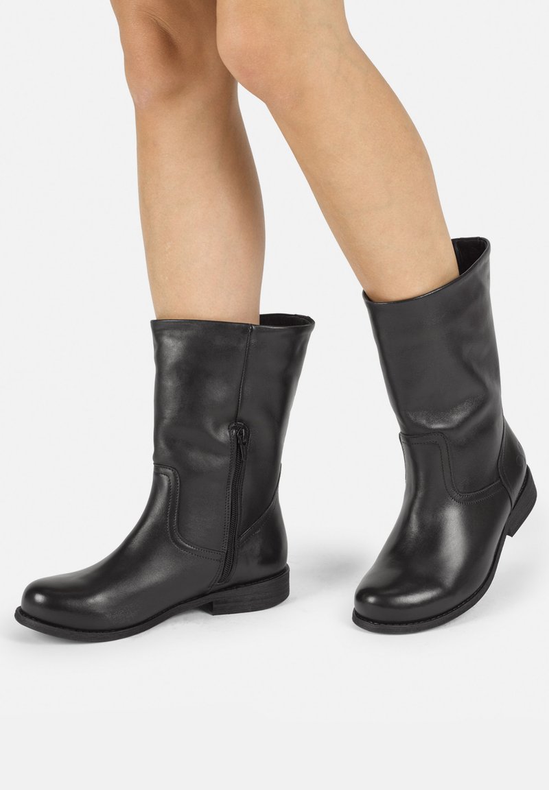 Botines de cuero negro hasta el tobillo con punta redonda, cremallera lateral y un tacón bajo texturizado. Acabado suave con un ligero brillo.