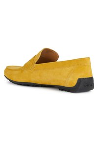 Mocassini gialli in suede con un profilo basso, dettagli cuciti e suola in gomma nera con il logo Geox. Texture liscia, design casual.