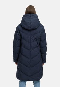 Jūras spēku puffer jaka ar kapuci, ar iešūtu chevron rakstu, garām piedurknēm un vidēja garuma dizainu, skatīta no aizmugures.