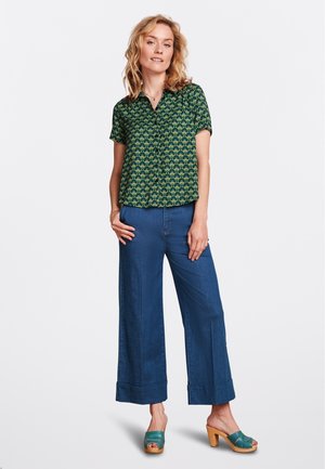 Chemise à manches courtes florale verte, assortie à un pantalon en denim bleu à jambes larges et des sabots à talons teal. Tissu doux avec un devant à boutons.