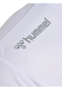 Witte sportkleding met een gestructureerd patroon, voorzien van een opvallend grijs "hummel" logo aan de zijkant. Stikseldetails zijn zichtbaar langs de naden.