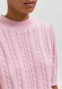 Hellrosa gestrickter Pullover mit hohem Kragen und kurzen Ärmeln, durchgehend mit einem strukturierten Zopfmuster und gerippten Akzenten.